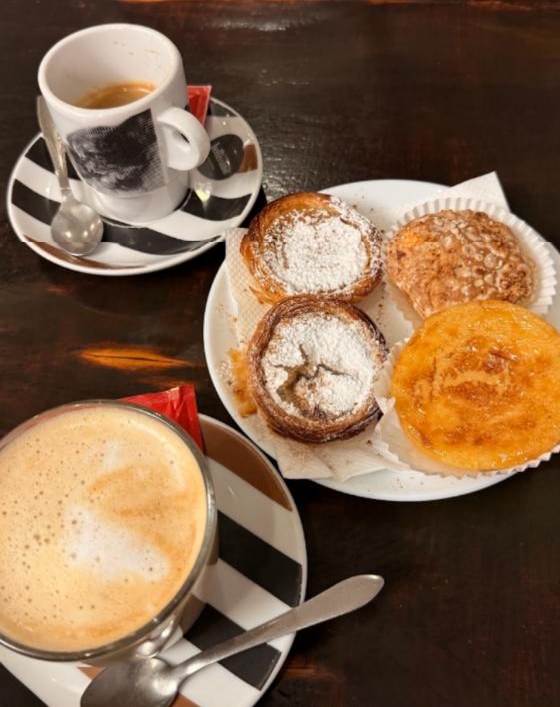 Pastéis com açúcar em pó e café à mesa na Alfama Doce