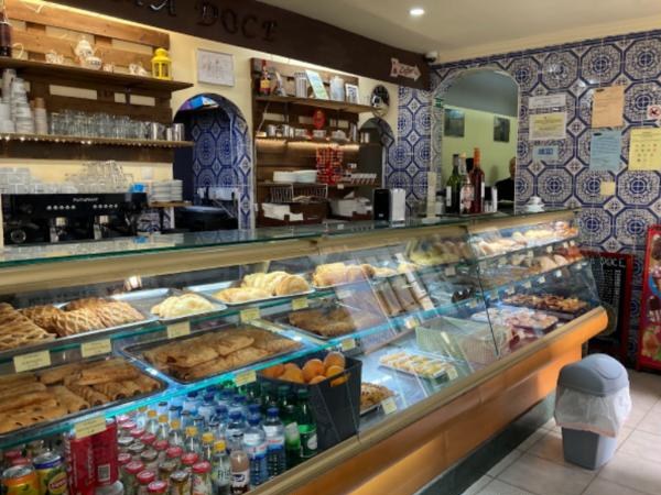 A vitrine da Alfama Doce com bolos e pastéis, e os azulejos azuis ao fundo